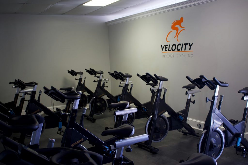 Row of spinning bikes with the velocity logo on the wall